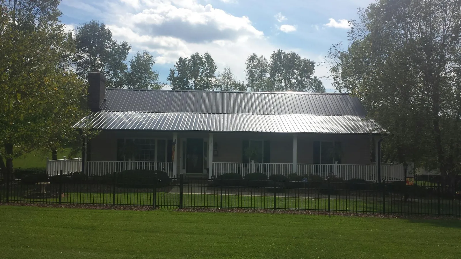 Gray metal roof on a brick ranch with a full width front porch — Gutter Guard Installation work by our crew in Bridgeton