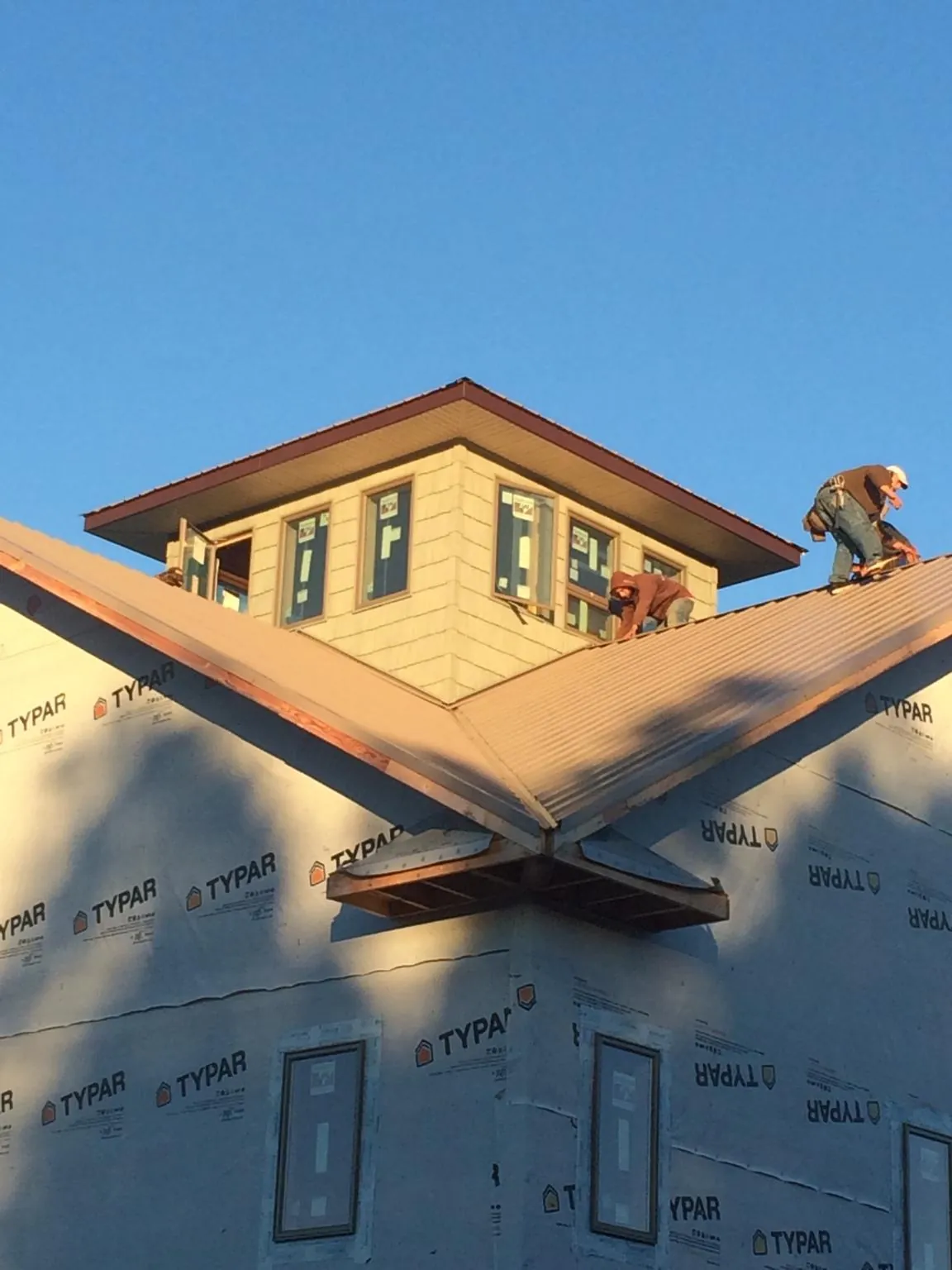 Roofers working around a rooftop cupola on a new metal roof at sunset — Roof Waterproofing in Bridgeton by Roofing Brothers